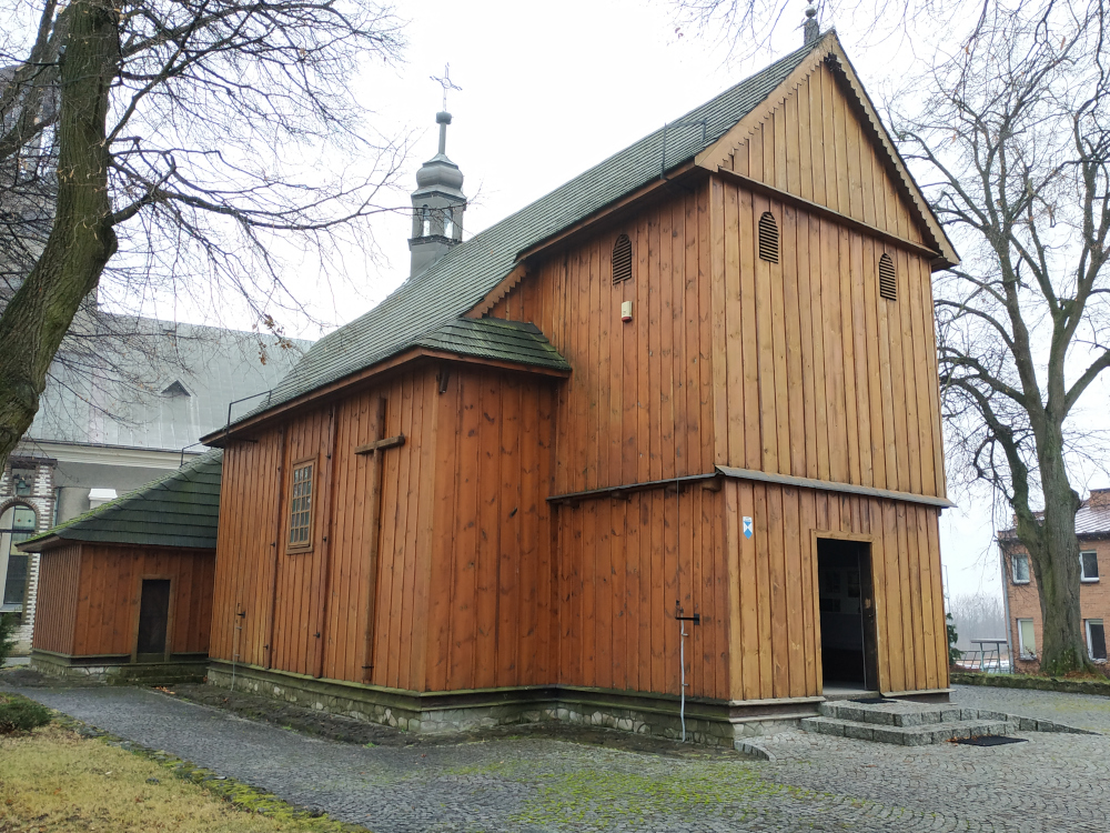 Drewniany, jasny kościół. Z przodu widoczne prostokątne wejście.