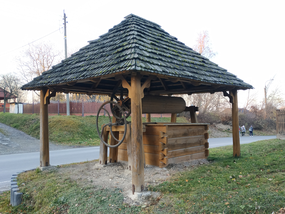 Drewniana stara studnia pod drewnianym zadaszeniem.